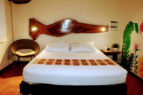 a bedroom with a bed with a wooden headboard at Hostal & Suites Pata de Perro in Bacalar