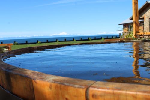 a large wooden tub filled with water with the ocean in the background at El Reflejo Lodge Spa - Queilen - Chiloé in Queilén