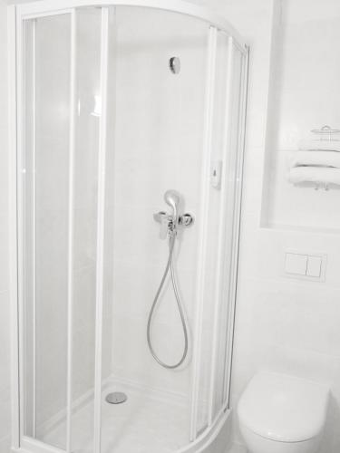 a white bathroom with a shower and a toilet at Brit Hotel Reims La Pompelle in Reims