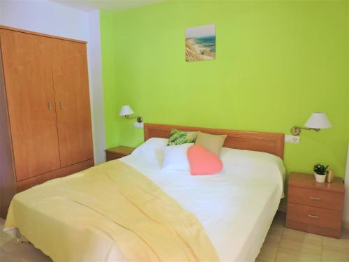 1 dormitorio verde con 1 cama con 2 almohadas en Apartamentos Inma Mayor en primera línea de playa, con Parking y Piscina, en Los Caños de Meca