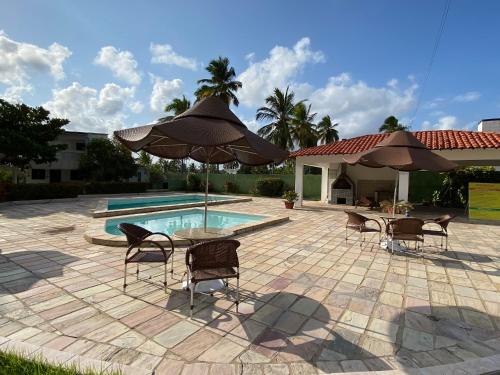 un patio con sillas, una sombrilla y una piscina en Casa Maragogi, Ponta de Mangue - AL, en Maragogi