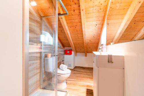 a bathroom with a toilet and a glass shower at Casa do Bairro by CosyCasa Praia Peniche in Peniche