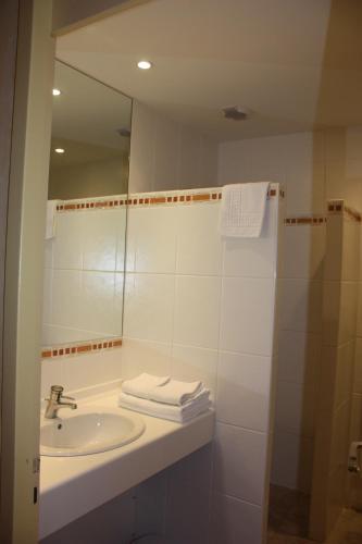 a white bathroom with a sink and a mirror at Hotel le Chalet in Gresse-en-Vercors
