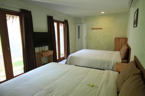a hotel room with two beds and a television at Bale Karang Cottages in Batukaras