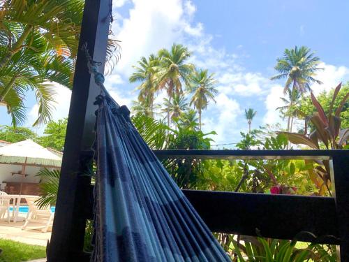a blue hammock on a balcony with palm trees at Pousada Luz do Porto in Porto De Galinhas