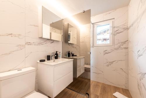 a white bathroom with a sink and a toilet at Central & Elegant Apartments,partially with Fireplace, by Zermatt Rental in Zermatt