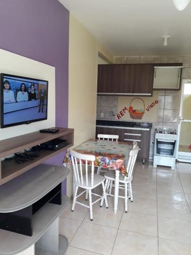 cocina con mesa con sillas y TV en Residencial Caxias, en Bombinhas