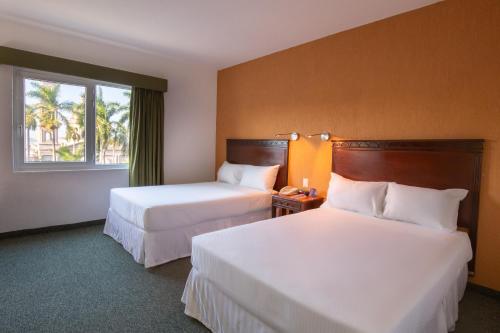 Habitación de hotel con 2 camas y ventana en HS HOTSSON Smart Value Tampico, en Tampico