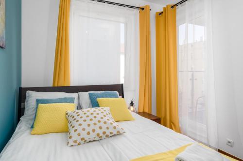 sypialnia z łóżkiem z żółtymi zasłonami w obiekcie Sleepway Apartments - Garbary 95-75D w Poznaniu