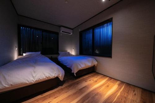 1 Schlafzimmer mit 2 Betten und 2 Fenstern in der Unterkunft Yufuin Kaze no Mori in Yufu