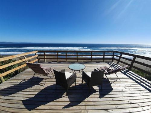 a wooden deck with a table and chairs and the ocean at Domos Curiñanco vista al mar in Valdivia