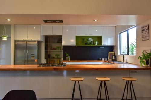 a kitchen with white cabinets and a counter with stools at Arthouse Six in Margaret River Town
