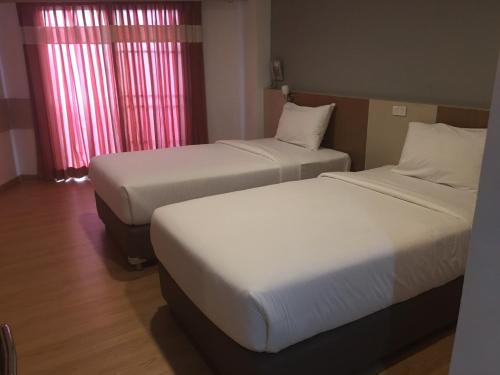 two beds in a hotel room with red curtains at Ingnaam Hotel in Ban Talat Rangsit
