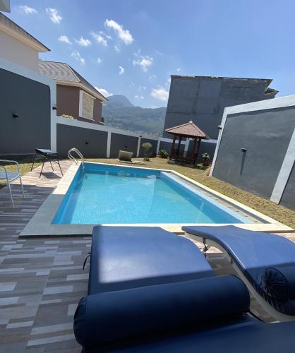 a swimming pool with two lounge chairs in front of a house at Marseillia Hills in Puncak