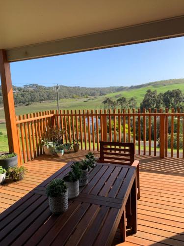 a wooden deck with a wooden table with potted plants at Villa 1 in Port Campbell