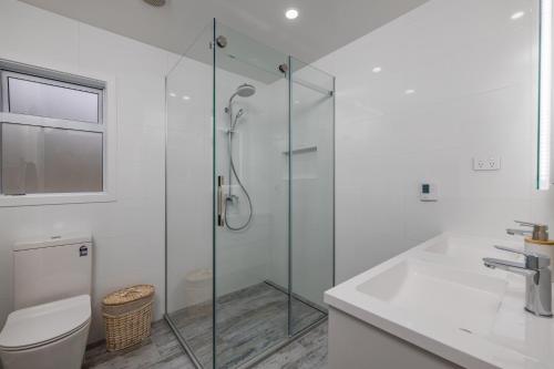 a bathroom with a shower and a toilet and a sink at Waterfront Beach House - Paihia Holiday Home in Paihia