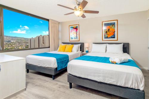 two beds in a room with a large window at Warm Aloha Vibes, Mountain Views, Short Walk to Beach, and Free Parking in Honolulu