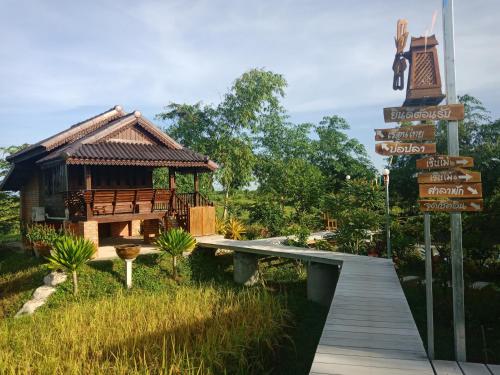 a wooden walkway leading to a small building with street signs at เรือนไทยใจสุขเอ๋ย in Ban Bang Wa