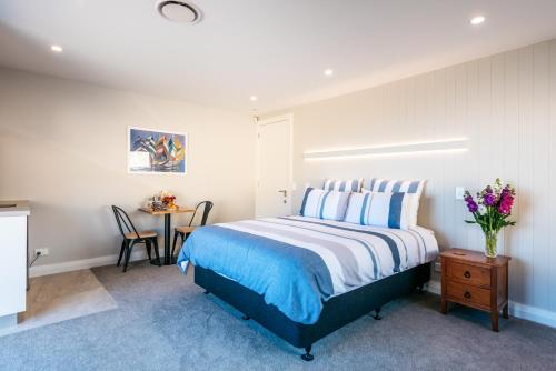 um quarto com uma cama e uma mesa com um vaso de flores em The Apartment - Sea Views at Te Whau Point by Waiheke Unlimited em Omiha