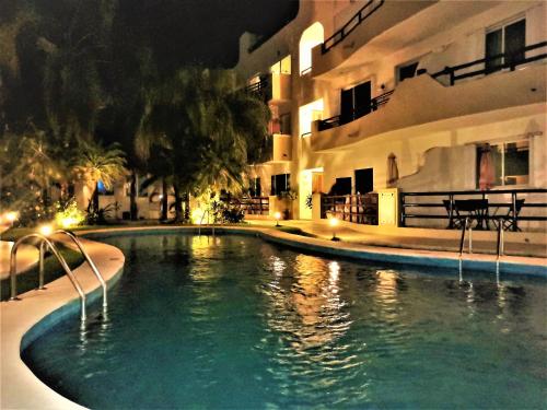 a swimming pool in front of a building at night at Margaritas Condo in Downtown of Playa in Playa del Carmen