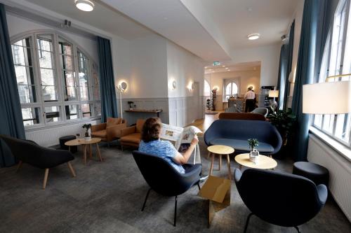 a woman sitting in a chair reading a newspaper in a hotel lobby at Hotel Bethel in Copenhagen