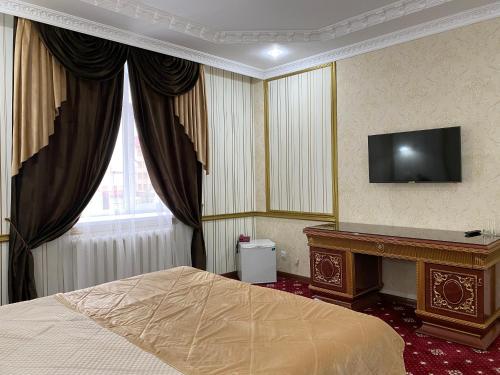 a bedroom with a bed and a tv on the wall at Lion Hotel in Astana