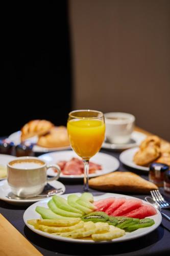 een tafel met borden en een glas sinaasappelsap bij Silken Ramblas in Barcelona