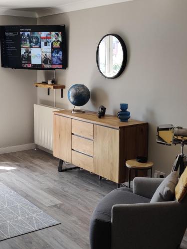 a living room with a wooden dresser and a mirror at Anchors Away in Ayr