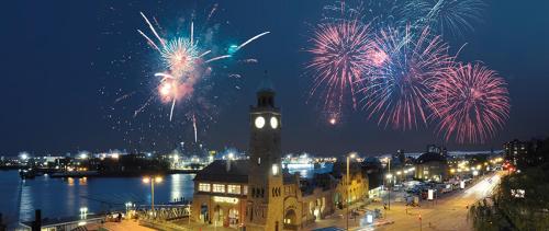 a building with a clock tower with fireworks in the sky at Cityhotel Monopol in Hamburg