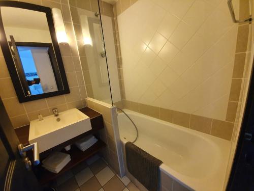 une salle de bain avec un lavabo, une baignoire et un miroir dans l'établissement Dans la résidence les jardins d opale, à Le Touquet-Paris-Plage