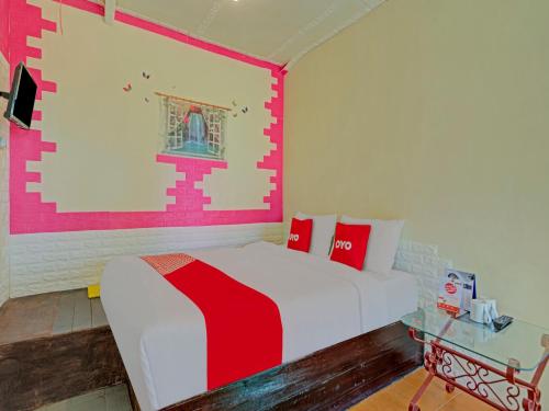 a bedroom with a red and white bed and a table at Super OYO 3208 Villa Inn App Trawas Bintaro Syariah in Kemloko-gede