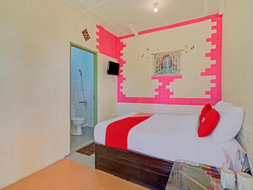 a bedroom with a red and white bed and a bathroom at Hotel O Villa Inn App Trawas Bintaro Syariah in Kemloko-gede
