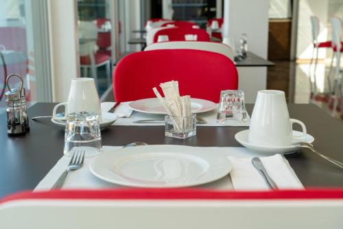 a table with white plates and a red chair at Nash Pratik Hotel in Geneva