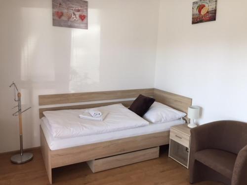 a bed with white sheets and a chair in a room at Penzión a Reštaurácia Harmónia Ostratice in Malé Ostratice