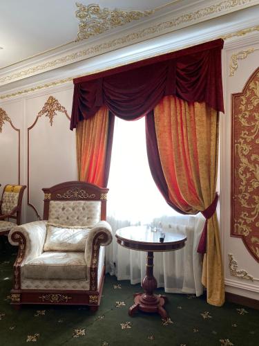 a room with a chair and a table and a window at Lion Hotel in Astana