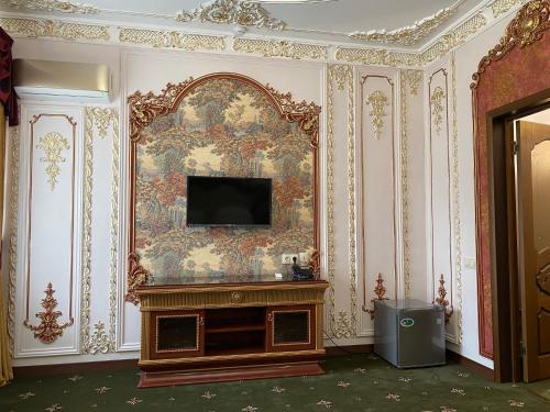 a room with a tv on a wall with a painting at Lion Hotel in Astana