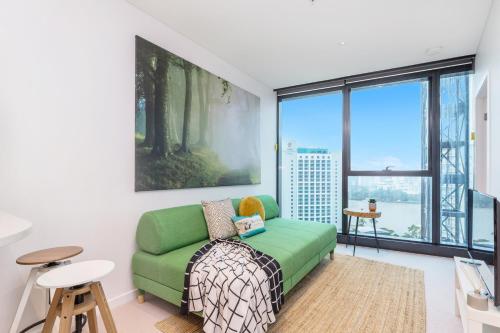 a living room with a green couch and a large window at KOZYGURU SKYTOWER BRISBANE CBD 2 BED APT QBN222-1815 in Brisbane