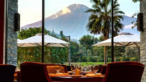 a table with wine glasses and a mountain in the background at Gran Melia Arusha in Arusha