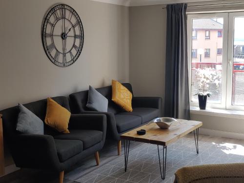 a living room with two couches and a clock on the wall at Anchors Away in Ayr
