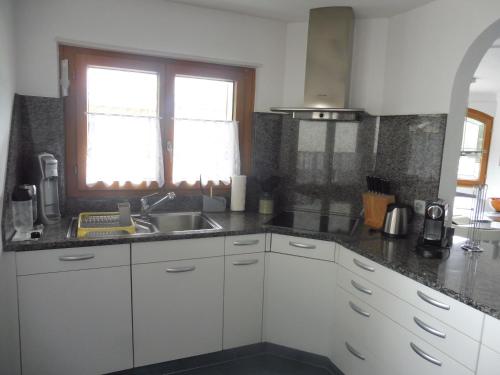 eine Küche mit weißen Schränken, einem Waschbecken und einem Fenster in der Unterkunft Apartment Theresli First Floor in Saas-Almagell