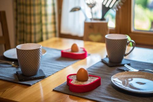 a table with two cups and two eggs on it at Ferienwohnung Gipfelblick in Grainau
