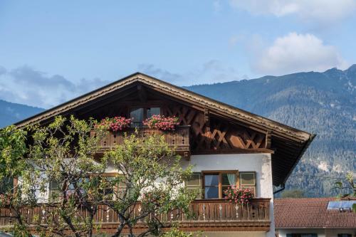 a house with a balcony with flowers on it at Ferienwohnung Gipfelblick in Grainau