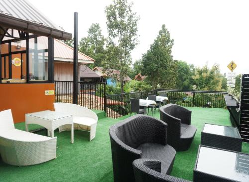 a patio with chairs and tables on a green lawn at Baansuan Chomchun in Amphoe Mae Taeng