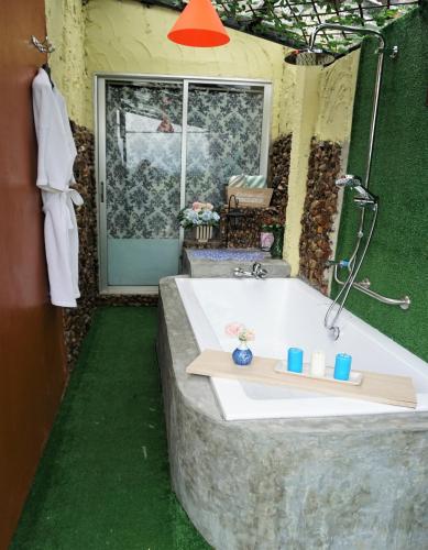 a bathroom with a large bath tub with green grass at Baansuan Chomchun in Amphoe Mae Taeng