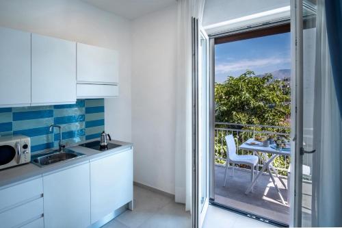 a kitchen with white cabinets and a balcony with a table at LEONE ROSSO APARTMENTs in Sorrento