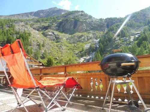 two chairs and a grill on a balcony with mountains at Apartment Theresli First Floor in Saas-Almagell
