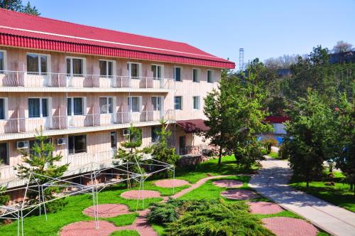an apartment building with a garden in front of it at Olympica Hotel in Almaty