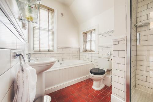 uma casa de banho branca com uma banheira, um WC e um lavatório. em Florence Gardens Boutique Hotel and Restaurant em Portsmouth
