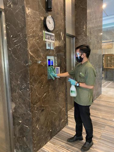 a man wearing a mask and gloves and a clock at Grande Valore Hotel Cikarang in Cikarang