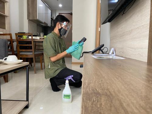 a man wearing a mask and gloves cleaning a counter at Grande Valore Hotel Cikarang in Cikarang